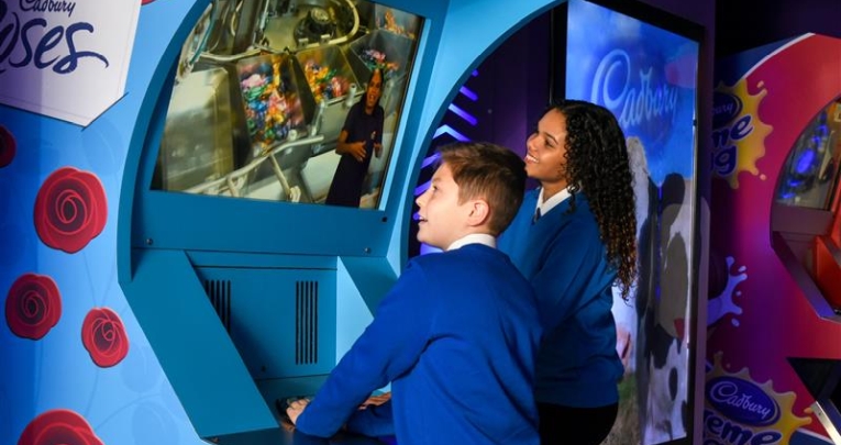 Two primary school children engaging with an interactive exhibit at Cadbury World
