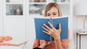 Girl reading book, representing writing for a purpose