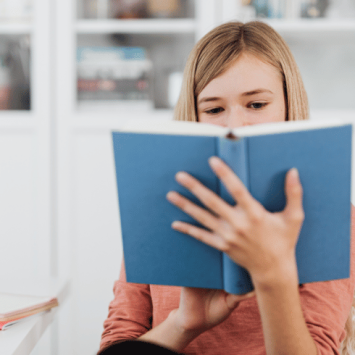 Girl reading book, representing writing for a purpose