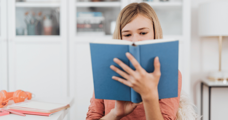 Girl reading book, representing writing for a purpose