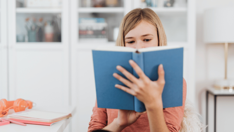 Girl reading book, representing writing for a purpose