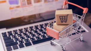 Mini shopping trolley on laptop keyboard, representing procurement in schools