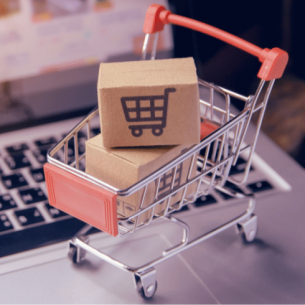 Mini shopping trolley on laptop keyboard, representing procurement in schools