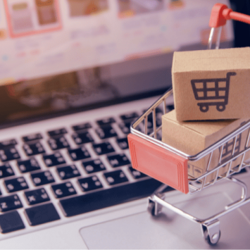 Mini shopping trolley on laptop keyboard, representing procurement in schools