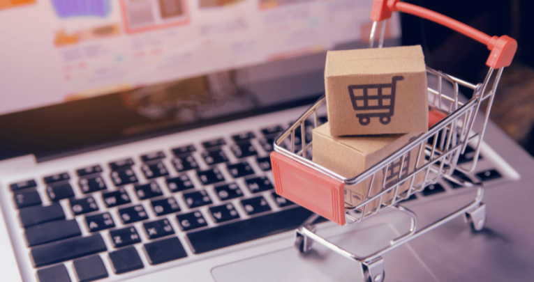 Mini shopping trolley on laptop keyboard, representing procurement in schools