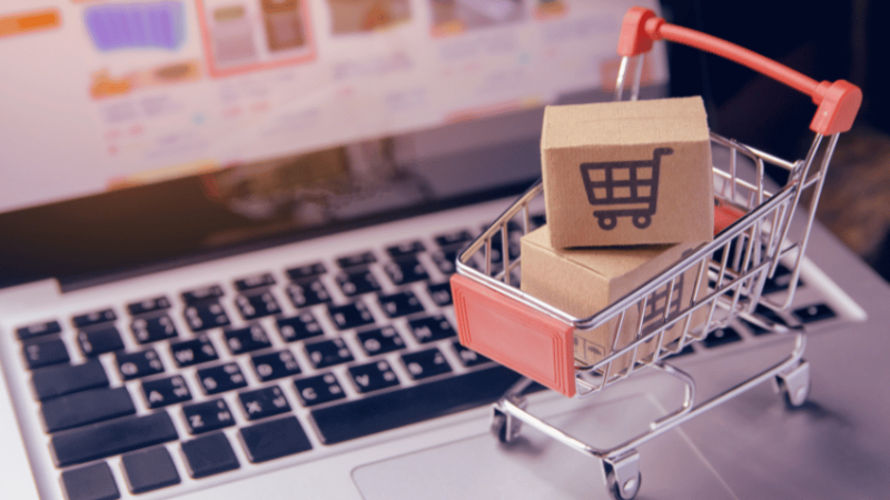 Mini shopping trolley on laptop keyboard, representing procurement in schools