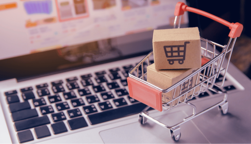 Mini shopping trolley on laptop keyboard, representing procurement in schools