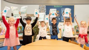 A group of primary school children holding Crest Award certificates