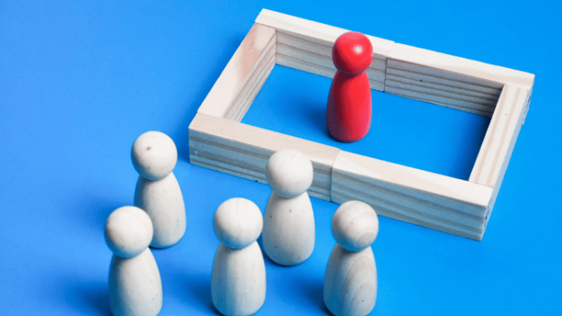 One wooden figure separated from others by a wall, representing audhd