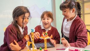 Three primary schoolgirls playing with LEGO