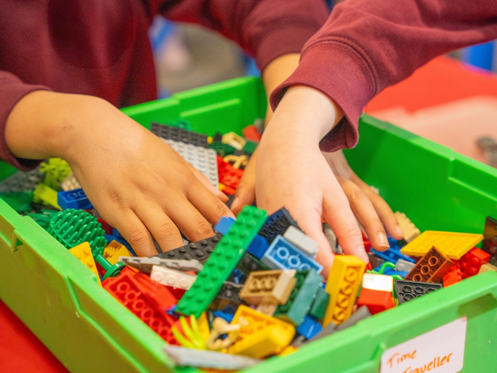 Children's hands in a box of LEGO