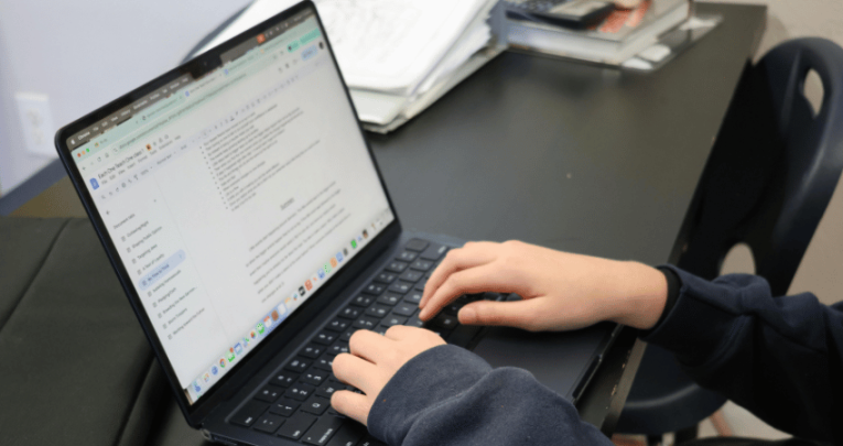 Teacher typing on laptop, representing SEND assessment tools