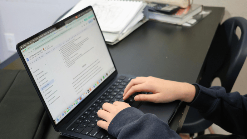 Teacher typing on laptop, representing SEND assessment tools